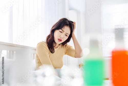 Young Asian Woman in Yellow Sweater Sitting on Bed, Holding Head in Pain, Suffering from Headache in Bright Morning Light Free Download Young Asian Woman in Yellow Sweater Sitting on Bed, Holding Head in Pain, Suffering from Headache in Bright Morning Light - GFXLoad