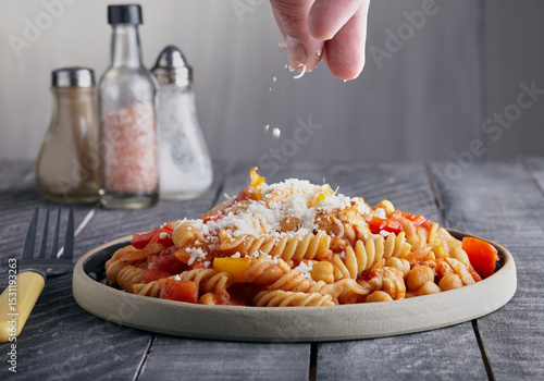 Chicken and pasta meal with cheeses being sprinkled over the top.