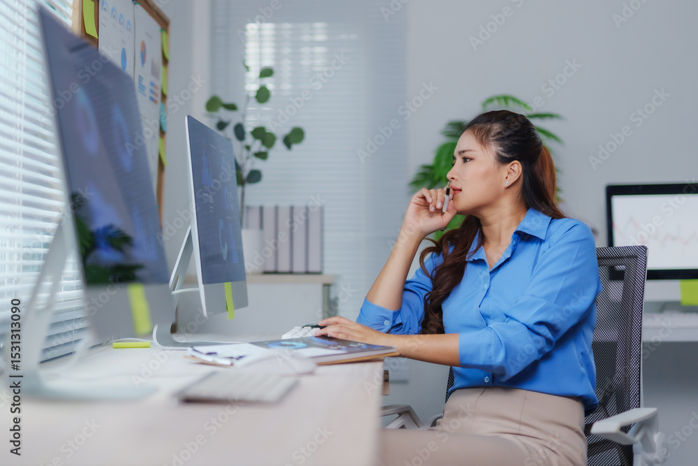 Obraz premium Pensive businesswoman analyzing charts and diagrams displayed on computer screen while working in office