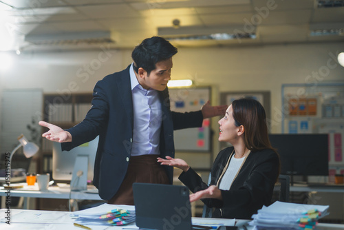 Fényképezés Two asian businesspeople are having a heated argument in the office at night, ex