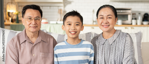 Fotografie Portrait of Asian family sitting on sofa smiling at camera