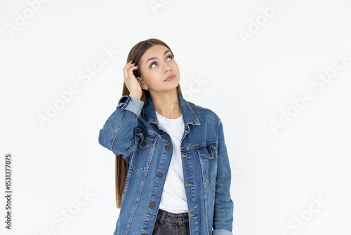 Young beautiful girl with long brown hair wearing jeans coat. freelancer looking away with confused disappointed expression, scratching head. student not remembers information for exam