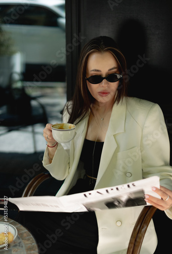Stylish woman drinking coffee with newspaper