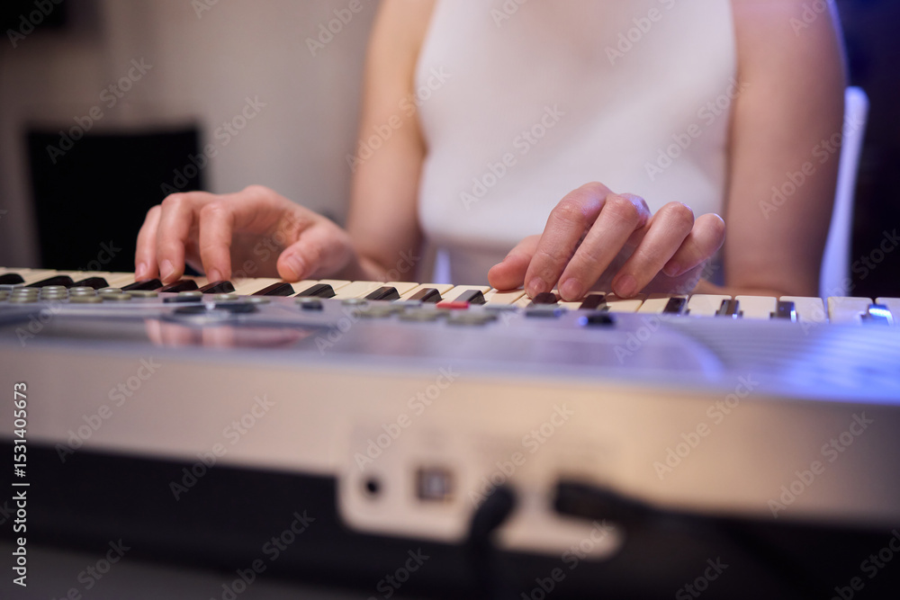 Fototapeta premium Hands play a keyboard in a modern studio, showcasing creativity and passion for music
