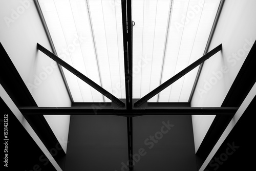 Black and white architectural photograph of steel ceiling beams with dramatic sunlight in museum interior