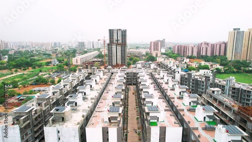 aerial drone shot flying low forward over similar houses with solar panels on roof showing affordable housing in Gurgaon, Delhi, Mumbai, Ahmedabad India