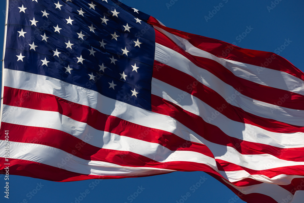 Obraz premium American Flag Waving In The Wind Against Deep Blue Sky.