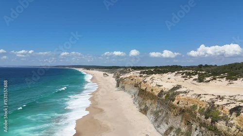High drone view above golden coastal cliffs and turquoise ocean waters near Lisbon. Aerial scene showcasing vivid textures between rock, sand, and clear Atlantic waves in soft sunlight.
