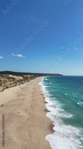 High drone view above golden coastal cliffs and turquoise ocean waters near Lisbon. Aerial scene showcasing vivid textures between rock, sand, and clear Atlantic waves in soft sunlight.

