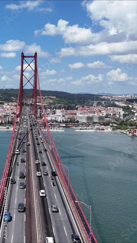Urban drone flight under the iconic 25 de Abril Bridge in Lisbon, Portugal. Aerial scene capturing the structure’s scale, water reflections, and vibrant city energy from a dynamic, low-angle view.

