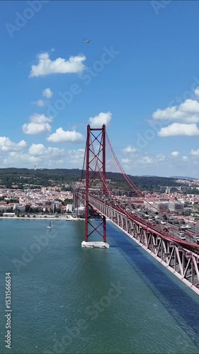 Urban drone flight under the iconic 25 de Abril Bridge in Lisbon, Portugal. Aerial scene capturing the structure’s scale, water reflections, and vibrant city energy from a dynamic, low-angle view.

