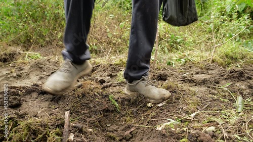 Farmer carefully covering corn seeds with feet, manually working agricultural field during traditional planting process in rural landscape