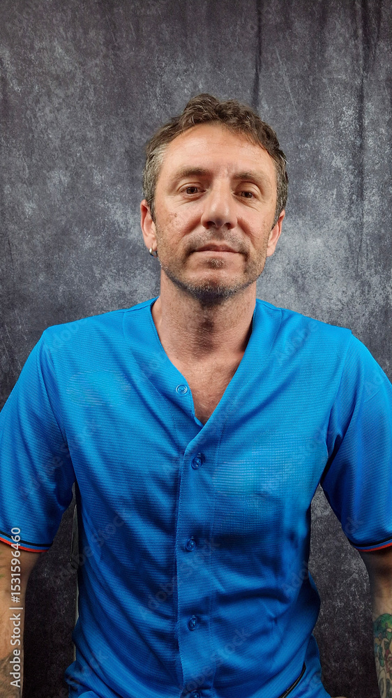 Portrait of man wearing a turquoise baseball shirt with buttons. The man is forty years old and is a caucasian with light eyes and hair, photographed on dark background Portrait of man wearing a turquoise baseball shirt with buttons. The man is forty years old and is a caucasian with light eyes and hair, photographed on dark background