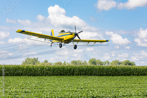 Crop duster airplane spraying chemicals on cornfield. Fungicide, pesticide and crop spraying concept.