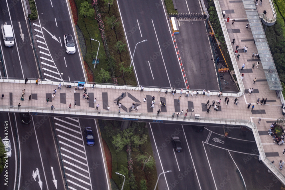 Obraz premium Top-down view of a busy pedestrian overpass crossing multilane urban roads, showcasing urban mobility, design, and city infrastructure flow.