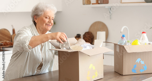 Obraz na plátně Senior woman with boxes of garbage in kitchen