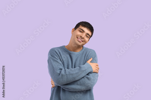 Young man hugging himself o...