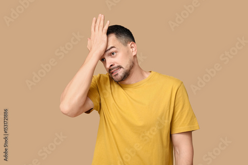 Photos Handsome ashamed young man covering face with hand on brown background