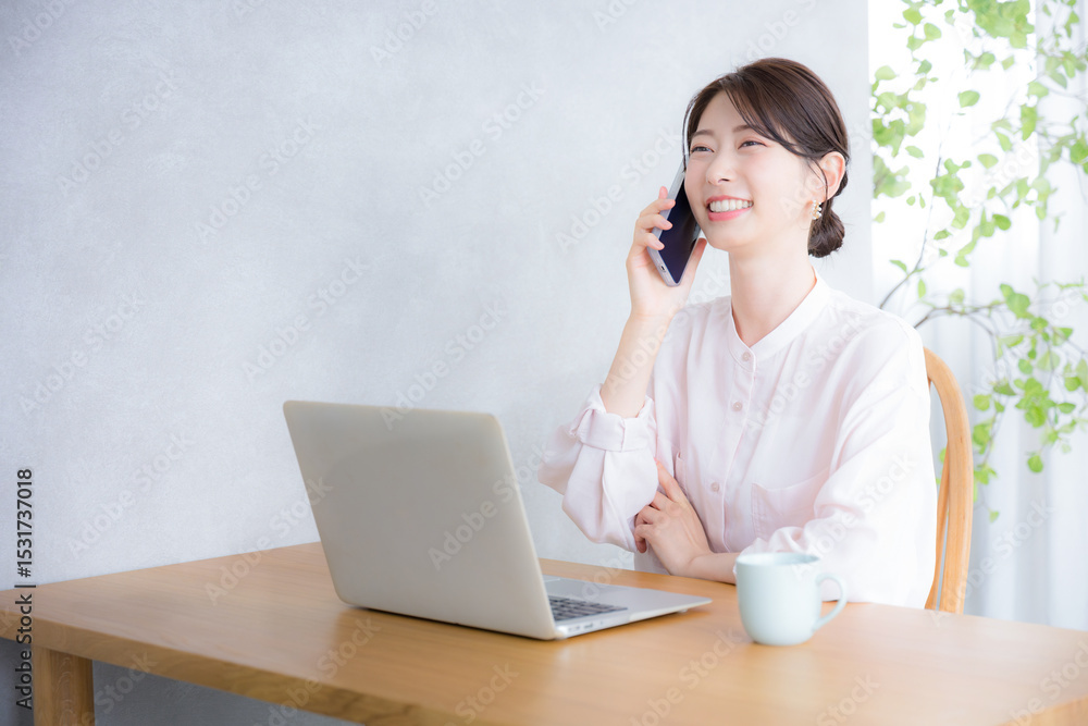 パソコンの前でスマホで通話や連絡をするコミュニケーションをとるシアーシャツのかわいい女性のビジネスシーン パソコンの前でスマホで通話や連絡をするコミュニケーションをとるシアーシャツのかわいい女性のビジネスシーン