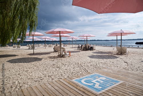 Wheelchair accessible rest area  for handicapped people on the public beach with the pink umbrellas