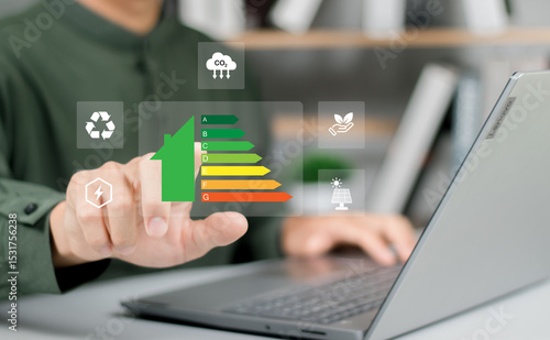 Hand of businessman using laptop with energy efficiency rating, Home improvement concept, ecological and bioenergetic house, efficiency scale.