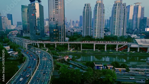 The urban view with high towers and two commuter trains and busy expressway in the afternoon