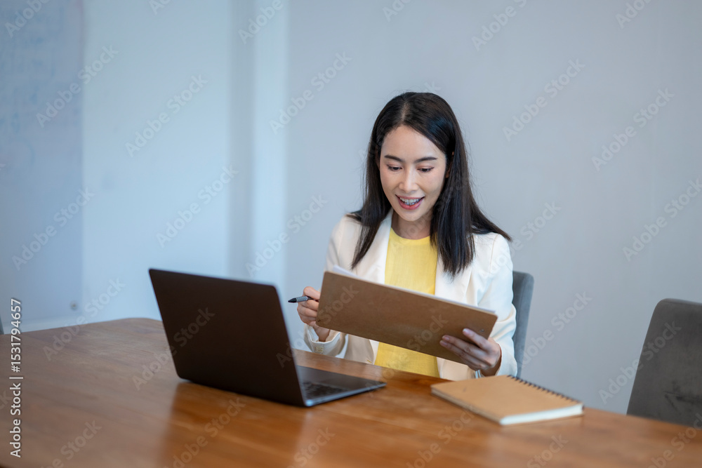 A woman is sitting at a desk with a laptop and a notebook A woman is sitting at a desk with a laptop and a notebook