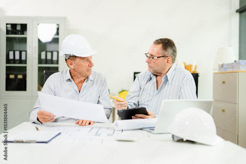 Obraz premium Construction engineers reviewing blueprints and tablet at desk. Team collaboration and planning for architecture or renovation project