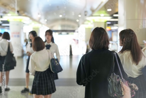 Photography In Shanghai, a group of Japanese high school girls in uniforms walk through an underground passage, chatting softly and staying close as they move along the rhythm of the city's morning commute
