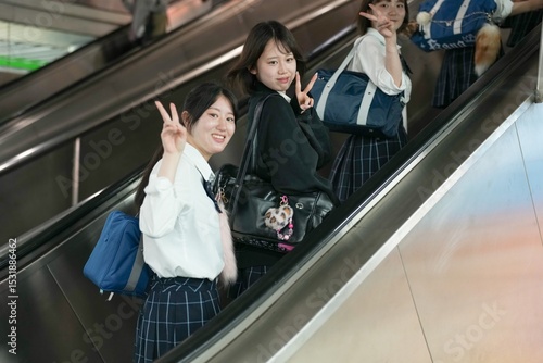 In Shanghai, a group of Japanese high school girls in uniforms ride an escalator together, chatting as they ascend, their uniforms reflecting the harmony of a shared commute in a foreign city.