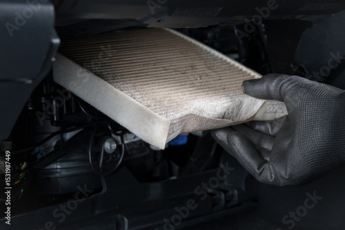 Mechanic Replacing a Dirty Cabin Air Filter in a Car Interior.Close-up of a gloved hand removing a dirty cabin air filter from a car 