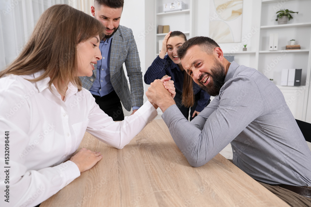 Obraz premium Businesspeople arm wrestling at wooden table in office