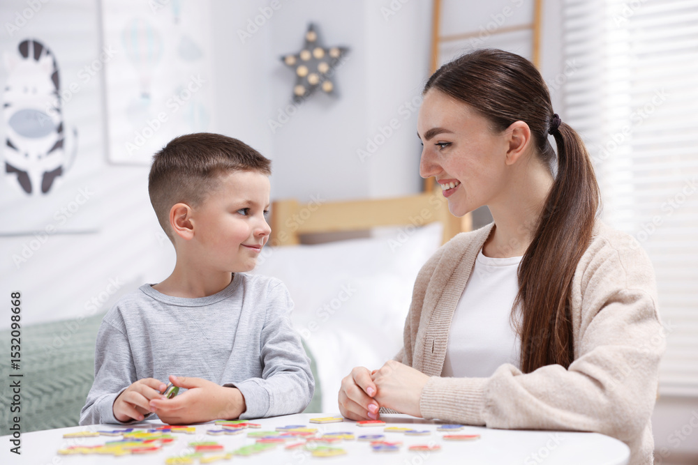 Fototapeta premium Dyslexia. Mother and her son learning letters at table indoors