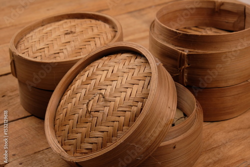 a collection of bamboo steamers and food containers made of woven bamboo on rustic brown wood. Indonesian traditional cooking ware. kukusan bambu. klakat bambu. Chinese bamboo cooking ware. dim sum. 