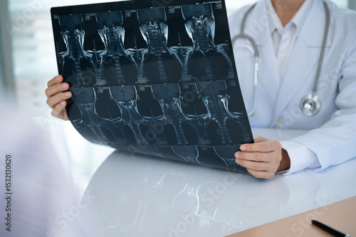 Orthopedist checkup cervical spine x-ray film and diagnose cervical spondylosis at doctor room.