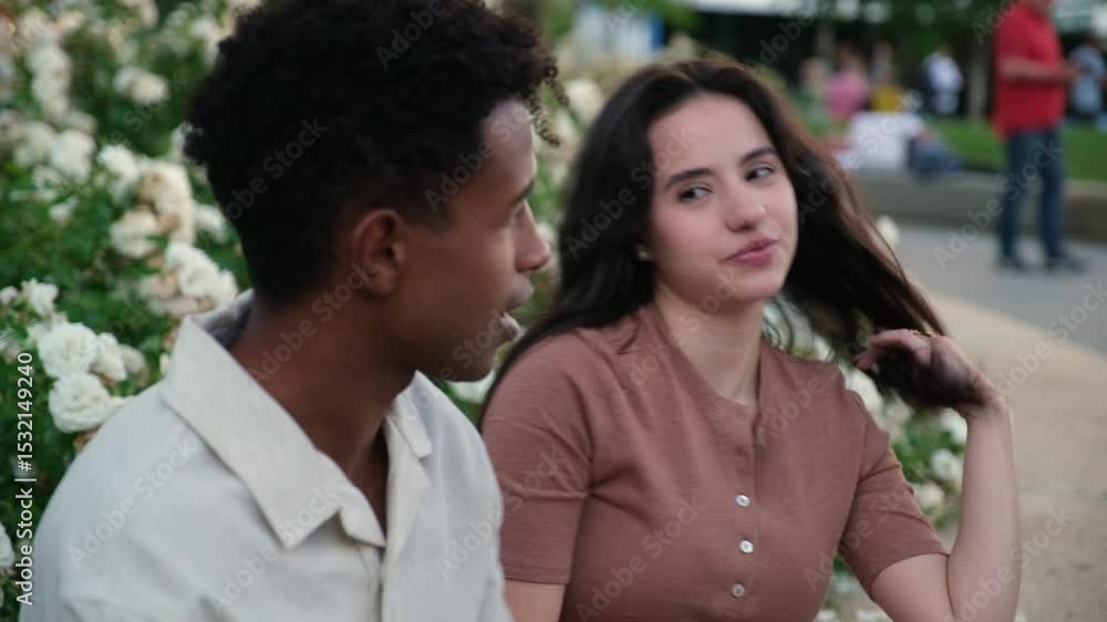 Young multi ethnic couple chatting and laughing together in a rose garden Young multi ethnic couple chatting and laughing together in a rose garden