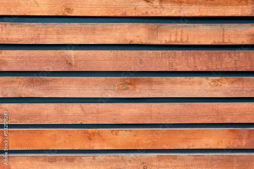 Decorative wooden fence made from pine slats, in close-up view. The natural wood texture and grain are clearly visible.