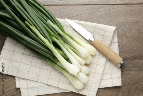 Fototapeta Naklejka Na Ścianę i Meble -  Fresh ripe green onions and knife on wooden table, flat lay