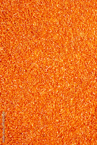 This is a detailed closeup view of a vibrant pile of orange glitter