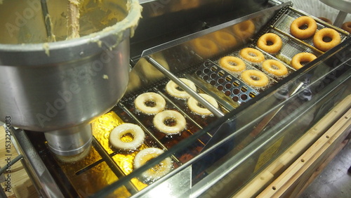 Fresh Donuts Frying in Commercial Deep Fryer. Fresh Donuts Being Made in Production Line.