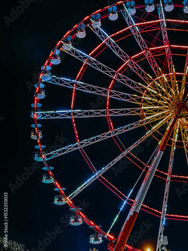 Half visible glowing Ferris wheel at night against dark sky

