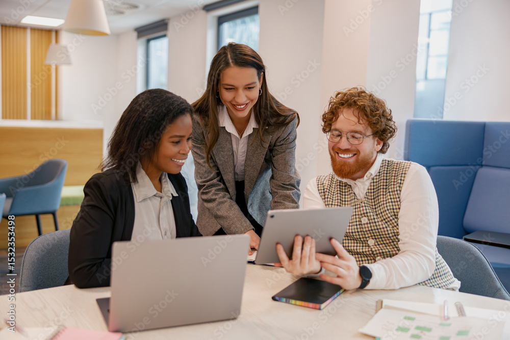 Fototapeta premium A diverse team works collaboratively using a digital device in a modern, contemporary workspace environment