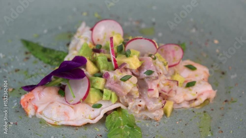 Delightful ceviche made with fresh dorade and shrimp, complemented by avocado and radish, garnished with an edible flower on a serene green plate.