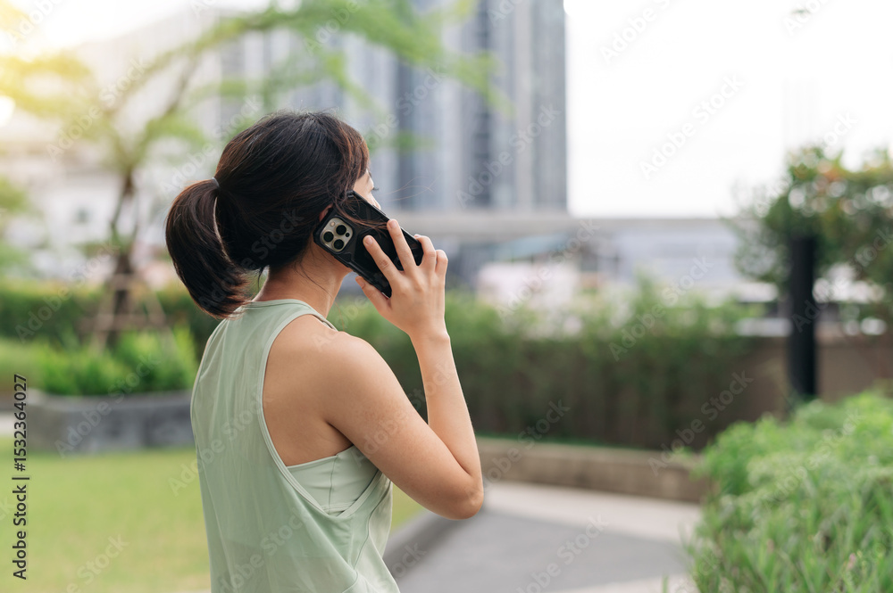 Asian woman in 30s gets fitness workout advice from trainer on smartphone. An exercise for healthy lifestyle and wellness with technology in an urban city at sunset for healthcare Asian woman in 30s gets fitness workout advice from trainer on smartphone. An exercise for healthy lifestyle and wellness with technology in an urban city at sunset for healthcare