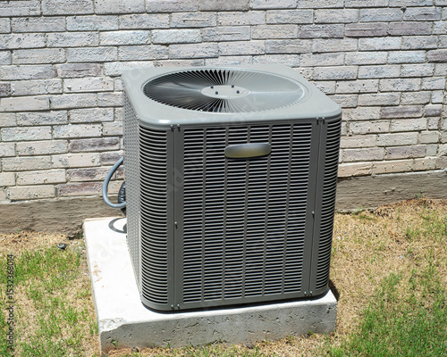Bild auf Leinwand Electrical and refrigerant lines of brand new outdoor central air conditioning unit installed on concrete pad brick house wall