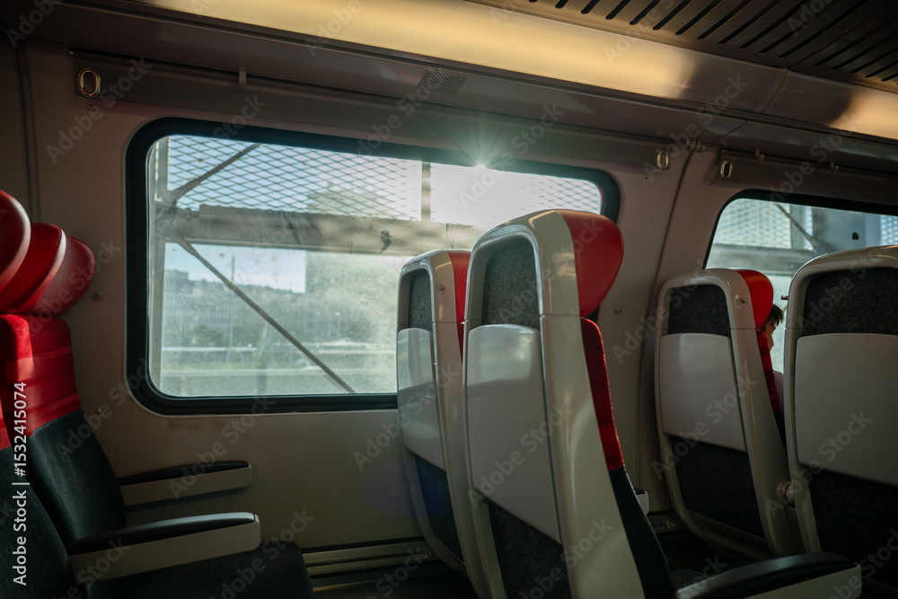 Fototapeta premium Empty red and black train seats beside window, concept of travel and transportation comfort