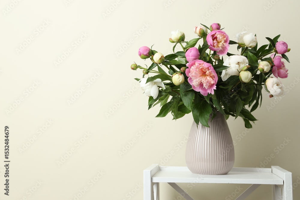 Obraz premium Bouquet of beautiful peony flowers in vase on shelving unit against beige background. Space for text