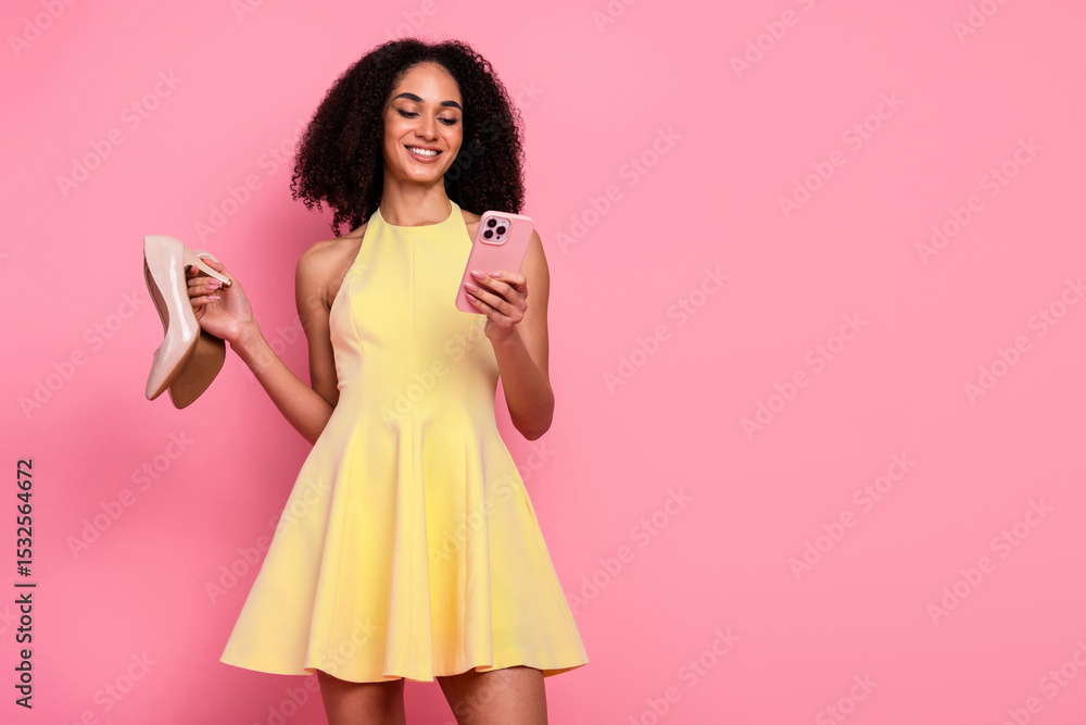 Young woman holding a phone and shoes, wearing a yellow dress against a pink background, expressing joy and style Young woman holding a phone and shoes, wearing a yellow dress against a pink background, expressing joy and style