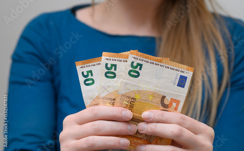 A woman holds euro banknotes in her hands, 150 euros
