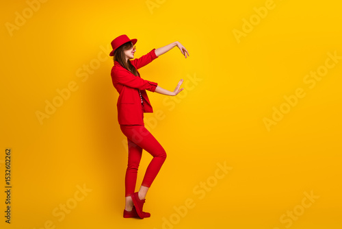 Bilde på lerret Attractive young woman wearing a red suit posed against a vibrant yellow backgro